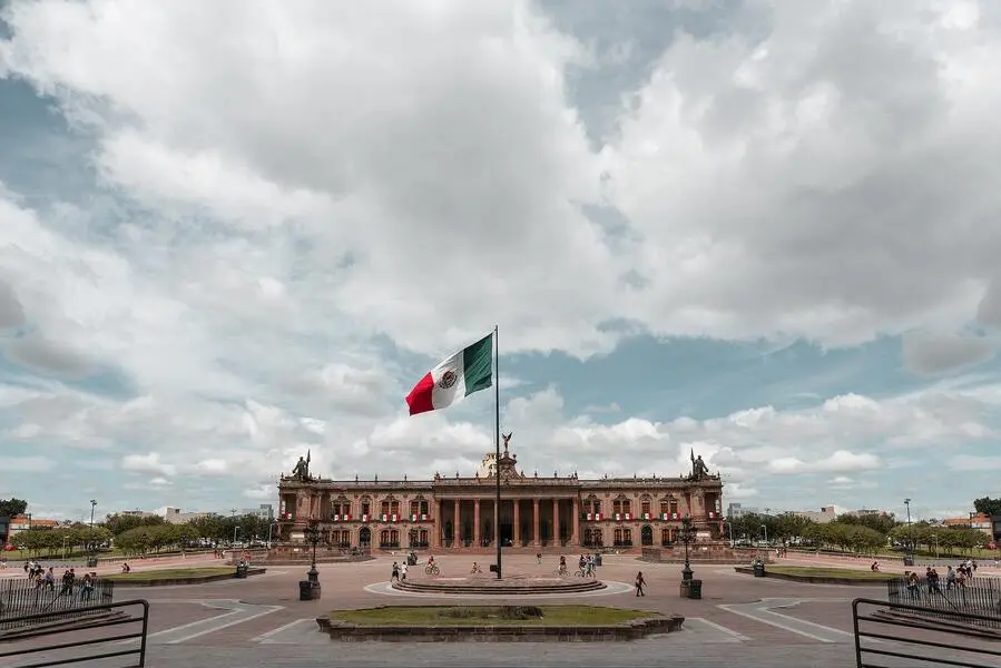 Vista do Museo Palacio de gobierno, na cidade de Monterrey num dia de sol e céu com nuvens, a frente se vê a bandeira do México hasteada. Reprodução Unsplash.