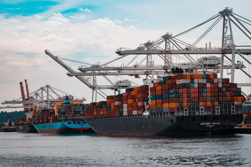 Navios em porto no alto mar com várias cargas de importação e exportação durante um dia claro com nuvens