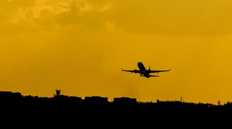 Avião em aeroporto de Miami subindo aos céus durante o fim da tarde