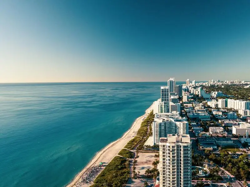 Quanto levar para gastar em Miami - Praia e mar de Miami com seus prédios e casa durante um dia de sol