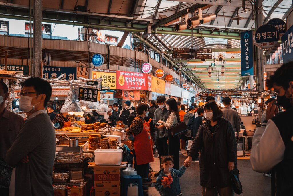 Mercado de alimentos na Coreia do Sul, com barracas e pessoas andando.