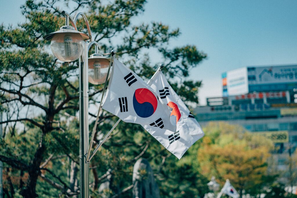 Imagem de duas bandeiras da Coreia do Sul em um poste na cidade. Quanto levar de dinheiro para Coreia do Sul