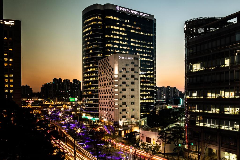 Imagem noturna, com vários prédios e uma avenida, na cidade de Seul. 